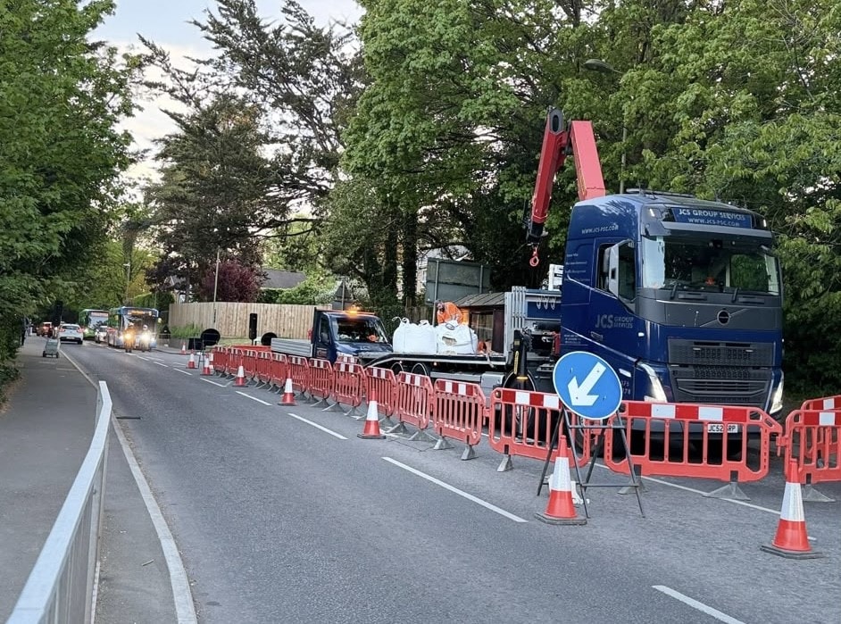 Highway maintenance truck and barriers creating a lane closure on a tree-lined road