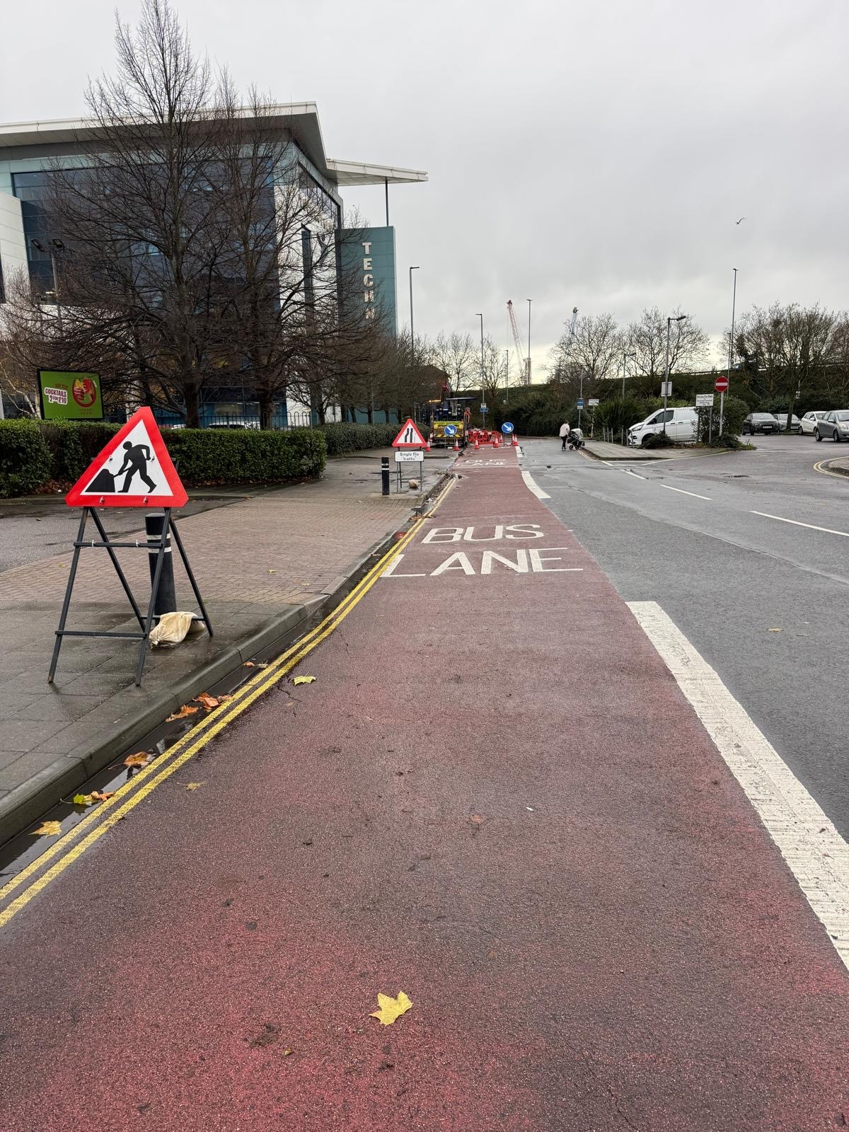 Road works ahead sign beside a bus lane with construction works in background